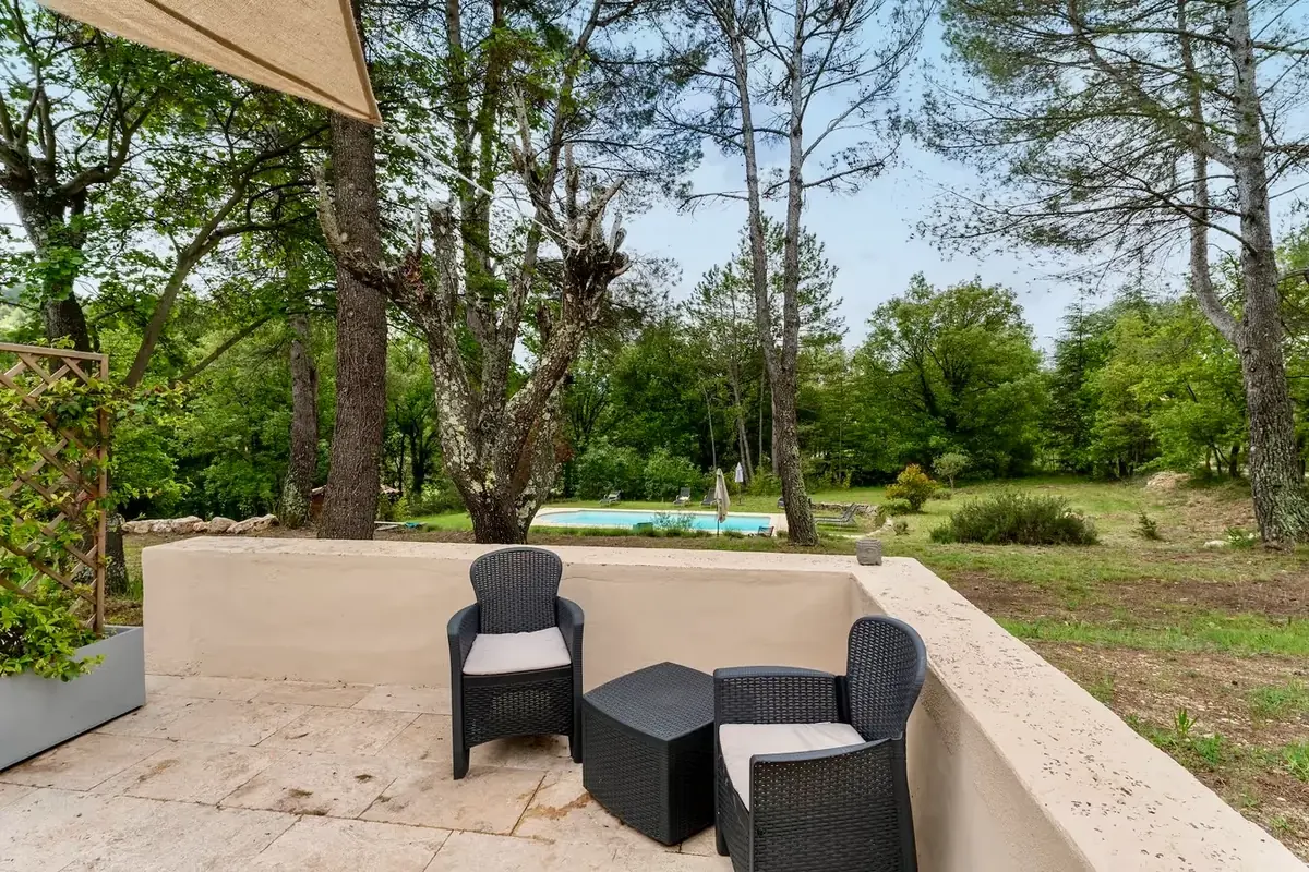Terrace with armchairs and a view of the pool through the pines